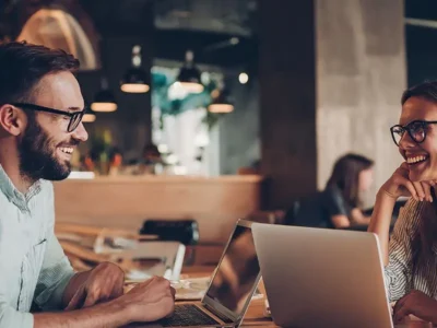 Two professionals working on laptops at a cafe in Los Cabos, with a relaxed indoor setting and a comfortable environment for remote work.