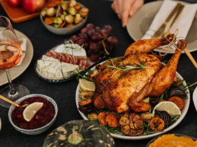 Roasted turkey served with seasonal vegetables, cranberries, and wine on a festive Thanksgiving table set for a shared holiday meal.